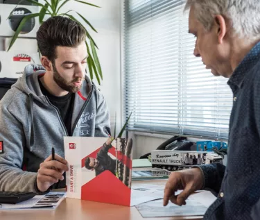 salesman talking with a client at his desk